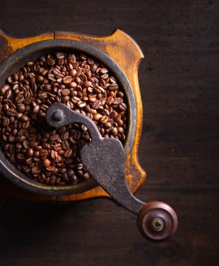 Ahşap bir masada kavrulmuş kahve çekirdekleri ile eski kahve öğütücüsü. Üst görünüm, alanı kopyala.