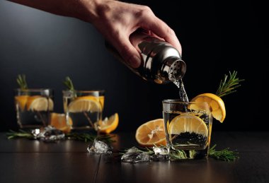 Limonlu ve biberiyeli kokteyl Cin ve Tonik. Barmen bardaktan bardağa kokteyl doldurur..