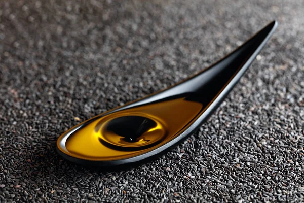 ごま油と黒ゴマ 小さな黒い皿の中の油の落下 — ストック写真