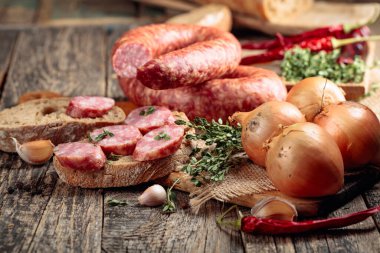 Ekmek ve baharatlı sosis eski ahşap bir masada. Kurutulmuş sosis, kekik, soğan, sarımsak ve biber.. 