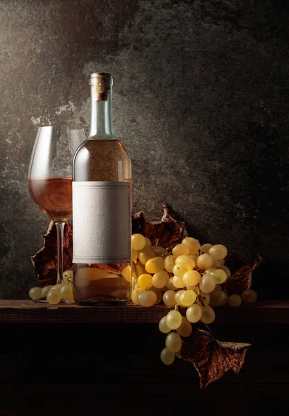 葡萄酒 葡萄和干枯的藤叶 木桌上装着空标签的瓶子 — 图库照片