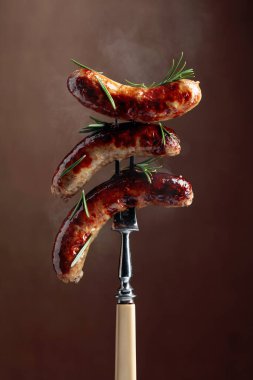 Biberiyeli ızgara Bavyera sosisi. Biberiye serpilmiş çatallı sosisler. Kahverengi arkaplan.
