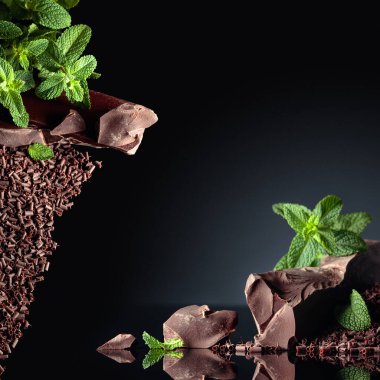 Siyah arka planda naneli koyu acı çikolata ve çikolata parçaları. Boşluğu kopyala.