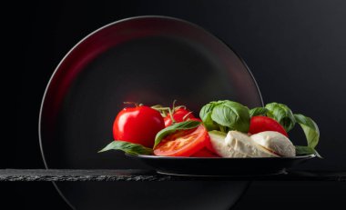 Siyah arka planda domates ve fesleğenli Mozzarella. Boşluğu kopyala.