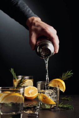 Limonlu ve biberiyeli kokteyl Cin ve Tonik. Barmen bardaktan bardağa kokteyl doldurur..