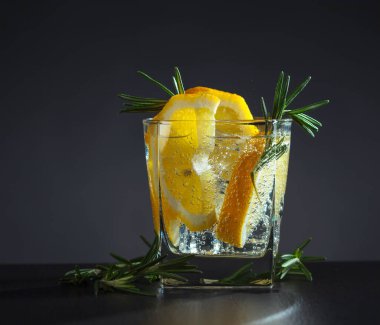 Koyu arkaplanda limon ve biberiyeli kokteyl ya da karbonatlı içecek..