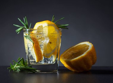 Koyu arkaplanda limon ve biberiyeli kokteyl ya da karbonatlı içecek..