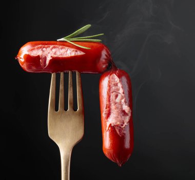 Izgara sosis ve çatalla biberiye. Siyah arkaplan, boşluğu kopyala. 