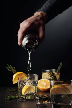 Limonlu ve biberiyeli kokteyl Cin ve Tonik. Barmen bardaktan bardağa kokteyl doldurur..