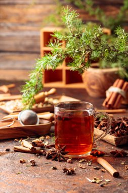 Tarçınlı, anasonlu ve kurutulmuş otlu Noel çayı. Kahverengi bir masada ardıç dallı bitki çayı..