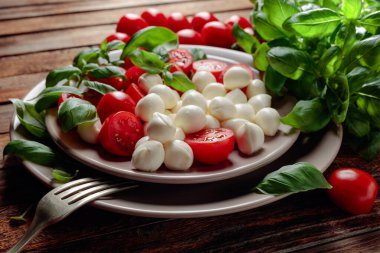 Eski ahşap bir masada domates ve fesleğenli Mozzarella..