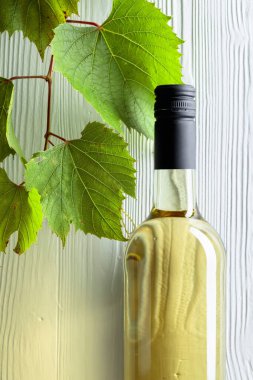 Açılmamış bir şişe beyaz şarap ve eski ahşap arka planda bir dedikodu. Boşluğu kopyala.