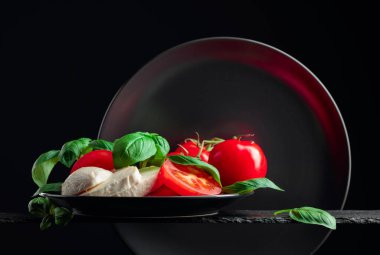 Siyah arka planda domates ve fesleğenli Mozzarella. Boşluğu kopyala.
