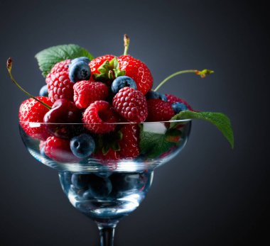 Çilek, yabanmersini, ahududu ve vişne karışımının koyu mavi arka planda bir stüdyoda yakın plan renkli bir karışımı..