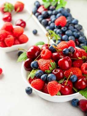Çilek, yabanmersini, ahududu ve vişne karışımının beyaz bir masada yakın plan renkli meyveleri..