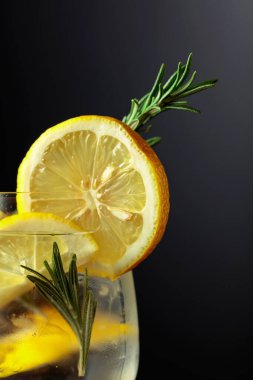 Limon dilimleri ve koyu arkaplanda biberiyeli kokteyl cin toniği..