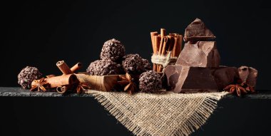 Çikolata, tarçın çubukları ve siyah arka planda anason. Boşluğu kopyala.