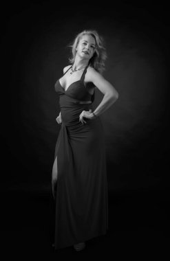 Gece elbisesi içindeki çekici orta yaşlı kadın. Siyah arka planda 40 yıllık sarışın mutlu. Siyah ve beyaz.