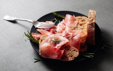 Siyah tabakta ekmek ve biberiyeli jambon..