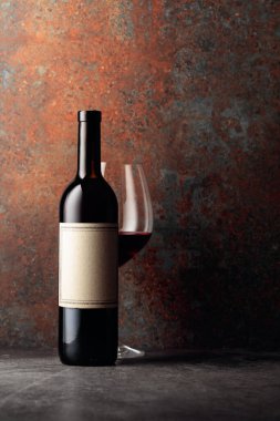 Paslı kahverengi arka planda eski boş etiketli bir şişe kırmızı şarap. Metnin için alanı olan ön görünüm.