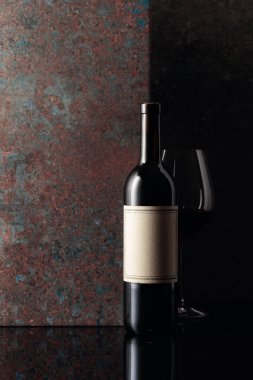 Paslı kahverengi arka planda eski boş etiketli bir şişe kırmızı şarap. Metnin için alanı olan ön görünüm.