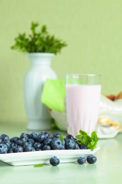 Mutfak masasında yaban mersinli yoğurt ve dut..