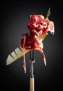 Prosciutto ve biberiyeli kavun. Kopyalama alanı olan siyah arkaplan.