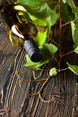 Açılmamış bir şişe beyaz şarap ve eski bir ahşap masanın üzerinde dedikodu. Boşluğu kopyala.