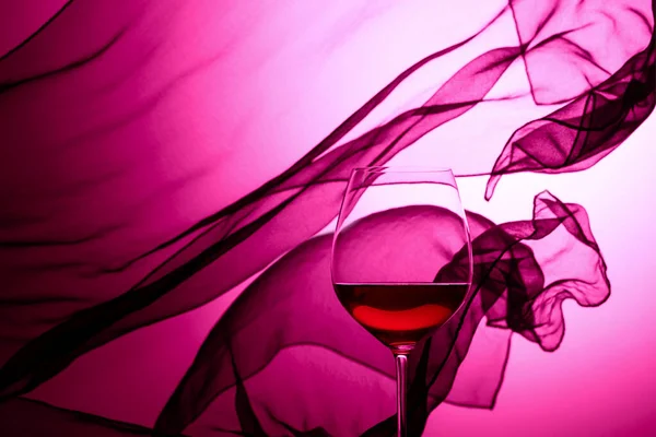 Bicchiere Vino Rosso Uno Sfondo Tenda Ondulante Raso Viola Retroilluminato — Foto Stock
