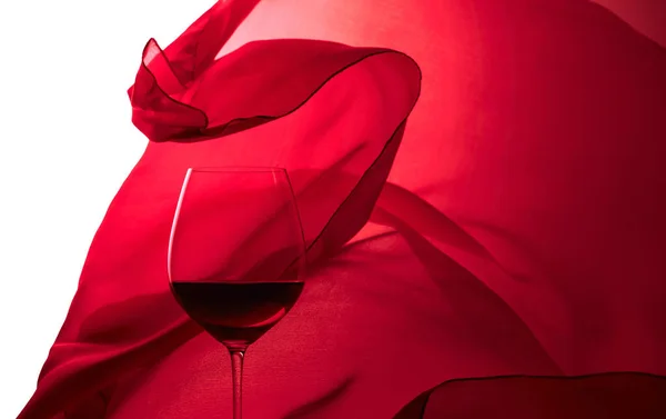 Ein Glas Rotwein Vor Dem Hintergrund Eines Winkenden Roten Satinvorhangs — Stockfoto