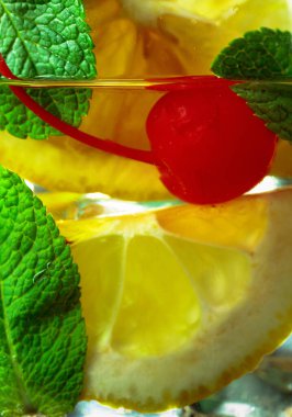 Limon dilimleri, kiraz ve nane ile soğuk, ferahlatıcı bir içecek. Makro çekim.