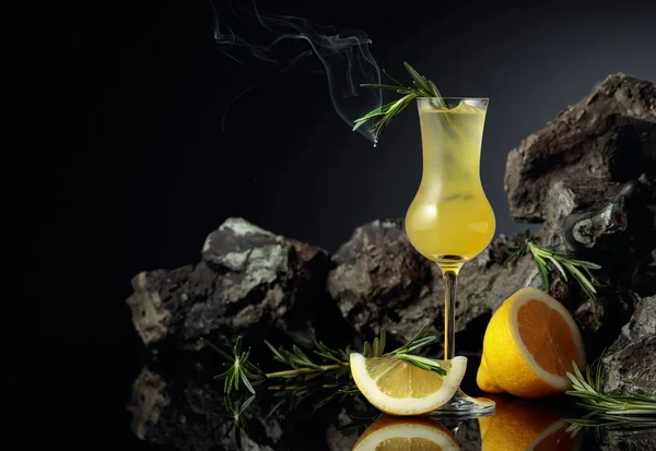 伝統的な自家製レモンリキュールのリモンチェッロと黒の反射的背景に新鮮な柑橘類 イタリアの伝統的なリキュールリモンチェッロにレモンスライスととろけるローズマリーの枝 — ストック写真