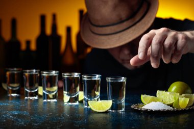 Şapkalı adam tuz ve limon dilimli tekila içiyor. Seçici odak.