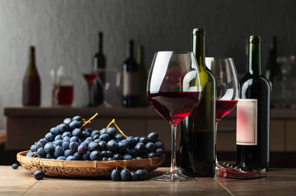 キッチンテーブルの上に赤ワインとブドウのグラスとボトル — ストック写真