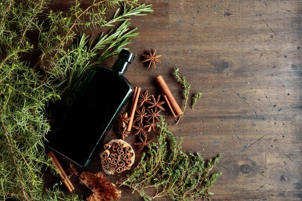 Vintage bottle, herbs, and spices on an old wooden table. Top view.