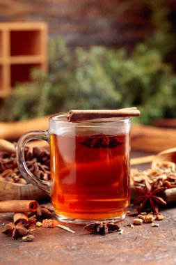 Tarçınlı, anasonlu ve kurutulmuş otlu Noel çayı. Eski kahverengi bir masada, ahşap tabaklarda baharatlı bitki çayı..