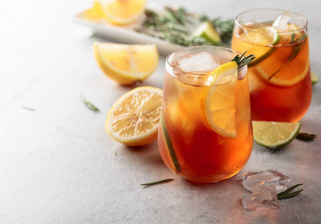 Iced tea with lemon, lime and ice garnished with rosemary twigs. Frozen glasses with citrus slices.