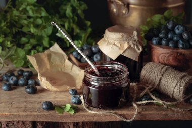 Eski ahşap bir masada taze böğürtlenli yabanmersini reçeli.