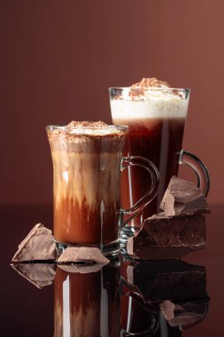 Krem şantili sıcak çikolata ve koyu kahverengi arka planda koyu çikolata parçaları.. 