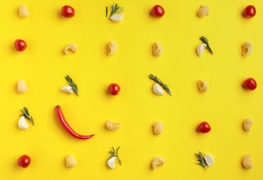 Sarı arka planda biber, sarımsak, domates ve biberiyeli makarna, yukarıdan görüş..