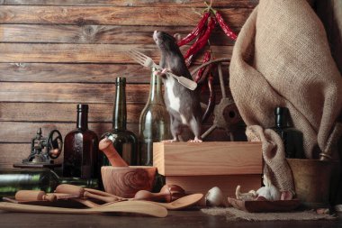 Masasında çatal ve eski mutfak aletleri olan komik bir fare..