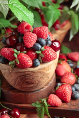 Yapraklı taze böğürtlen. Eski bir masada çilek, ahududu, yabanmersini ve tatlı kirazlar.. 