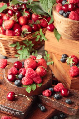 Yapraklı taze böğürtlen. Çilek, ahududu, böğürtlen ve kirazlar eski ahşap bir masada.. 
