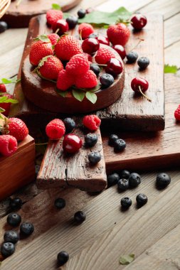 Yapraklı taze böğürtlen. Çilek, ahududu, böğürtlen ve kirazlar eski ahşap bir masada.. 