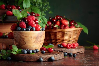 Yapraklı taze böğürtlen. Eski bir masada çilek, ahududu, yabanmersini ve tatlı kirazlar. Boşluğu kopyala.