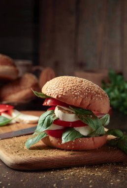 Eski ahşap bir masada mozzarella, domates ve fesleğenli sandviç. Boşluğu kopyala.