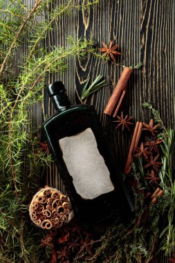 Eski bir ahşap masada antika bir şişe, otlar ve baharatlar. Eski boş bir şişede.