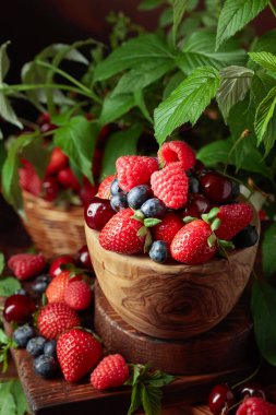 Yapraklı taze böğürtlen. Eski bir masada çilek, ahududu, yabanmersini ve tatlı kirazlar.. 