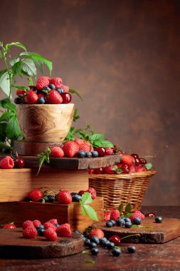 Yapraklı taze böğürtlen. Eski bir masada çilek, ahududu, yabanmersini ve tatlı kirazlar. Boşluğu kopyala.