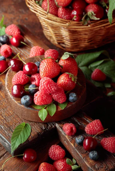 Yapraklı taze böğürtlen. Eski bir masada çilek, ahududu, yabanmersini ve tatlı kirazlar.. 